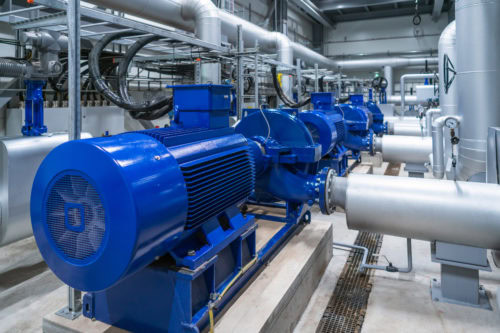 Industrial pumps with blue motor housings and pipes in a facility setting.