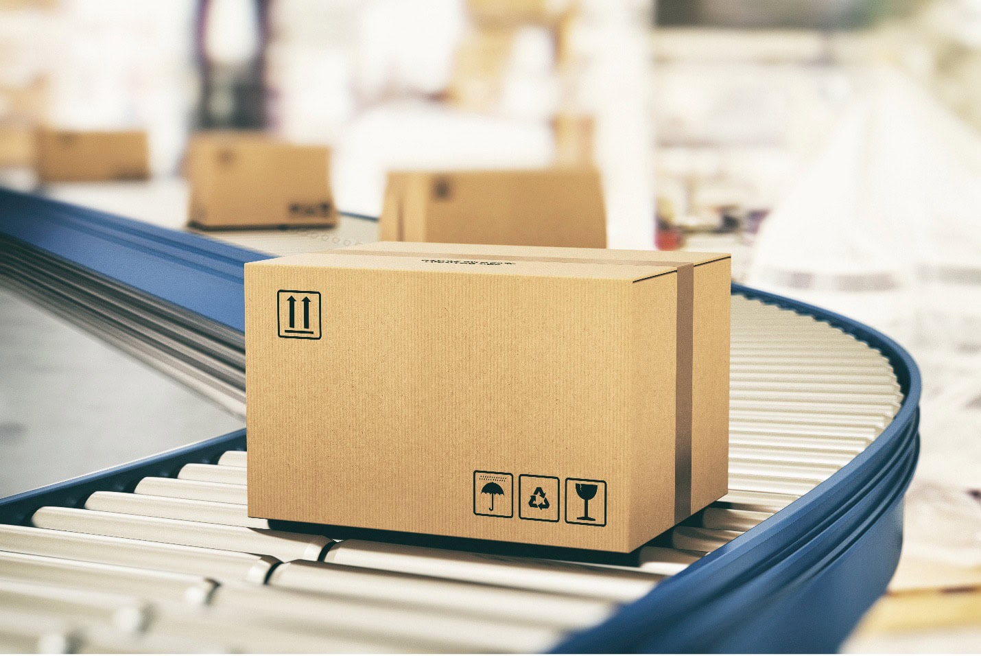 Caja de cartón con símbolos que indican frágil y reciclable, colocada sobre una cinta transportadora en movimiento en un almacén.